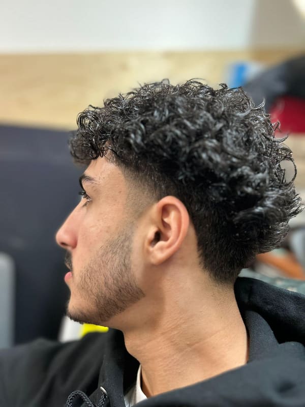 Curly hair left long on top with a clean taper on the sides