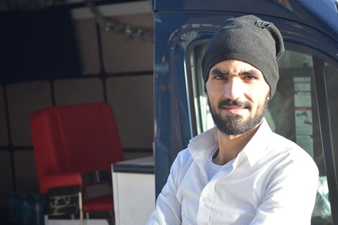 Mohammad in a white shirt and black beanie inside the van